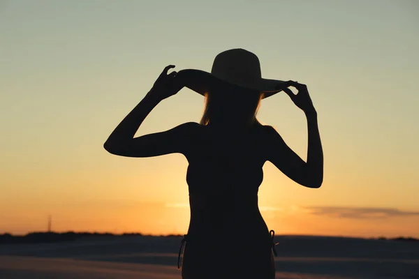Silhouette de belle femme posant avec chapeau dans le désert d'or au coucher du soleil — Photo