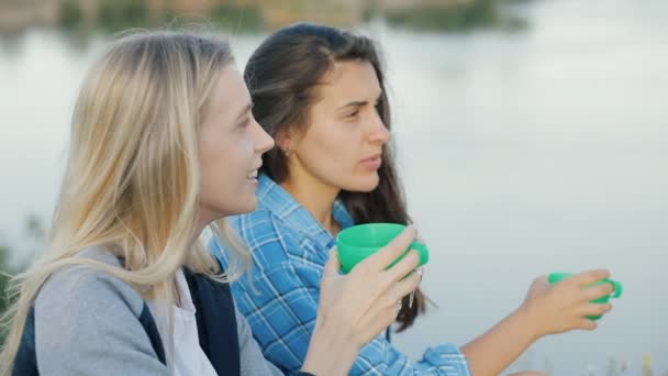 Mejores amigos caminando juntos. Dos mujeres jóvenes tomando té caliente al aire libre. Las niñas viajan con aventura . — Vídeos de Stock