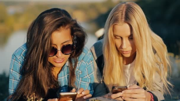 Due giovani viaggiatrici. Migliori amici sdraiati a terra e guardare giù per gli smartphone . — Video Stock