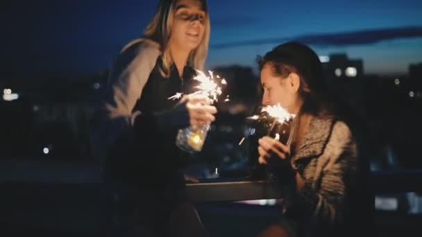 Feliz mujer amigos divirtiéndose con bengalas en la azotea en cámara lenta — Vídeo de stock