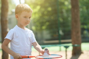Küçük çocuk bir çam ormanı, bir doğa, aktif dinlenme badminton oynuyor