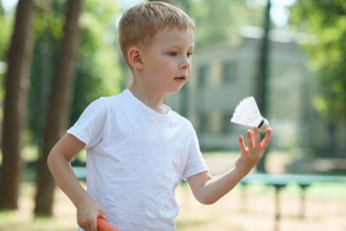 Küçük çocuk bir çam ormanı, bir doğa, aktif dinlenme badminton oynuyor