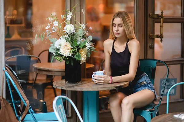 Donna seduta in un caffè tristemente cercando di tazza di caffè in serata e pensando — Foto Stock