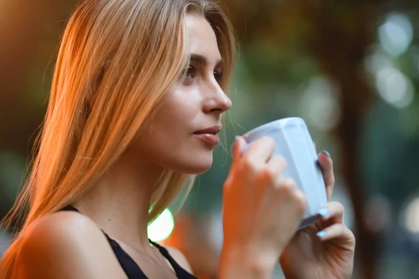 En kvinne som sitter på en kafe og drikker deilig latte. Kaffepause utendørs om kvelden . – stockfoto