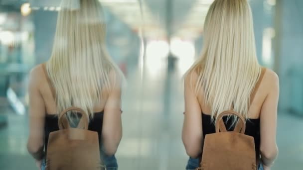 Mulher em um corredor de shopping voltar, espelhando em vidro — Vídeo de Stock