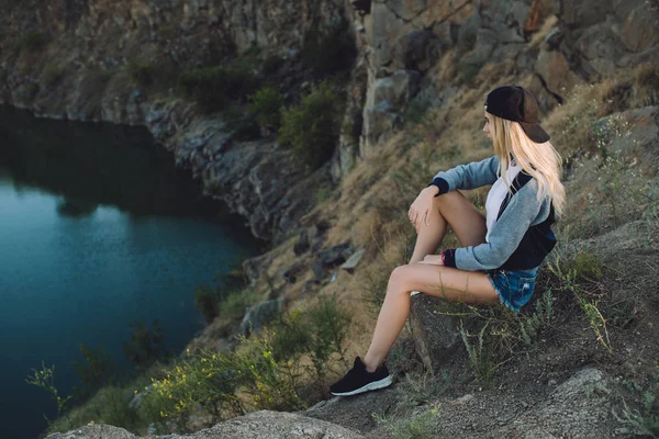 Chica excursionista. Viaje solo. Mujer joven viaja con aventura. Se sienta en la naturaleza y mira a la cantera . —  Fotos de Stock