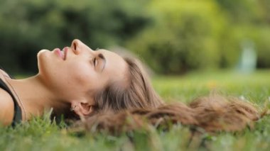 Yaz aylarında çim üzerinde yalan güzel çekici kadın o sakin, dön ve Kameraya gülümse.