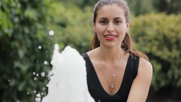 Una mujer guapa se lava la cara de la fuente en cámara lenta. Agua fresca en un cálido día de verano . — Vídeos de Stock