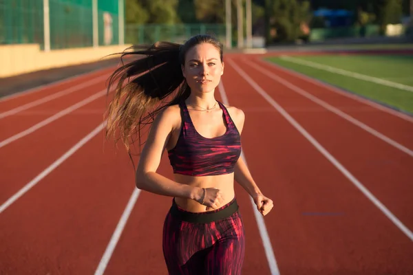 Deportista profesional atleta velocista corriendo en pista de estadio por la noche. Concepto de estilo de vida saludable. Adelante a la victoria . — Foto de Stock