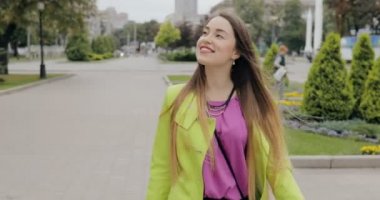 Bulutlu yaz veya sonbahar günü, steadicam atış şehir sokakta yürüyen mutlu kadın