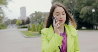 Mutlu kadın şehir sokakta bulutlu yaz veya sonbahar günü, steadicam atış yürüyüş smartphone tarafından konuşma