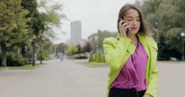 Mutlu kadın şehir sokakta bulutlu yaz veya sonbahar günü, steadicam atış yürüyüş smartphone tarafından konuşma
