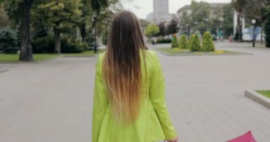 Yaz veya sonbahar günü, arkadan görünüm, steadicam vurdu şehir sokakta şemsiyesi altında yürüyen kadın bulutlu