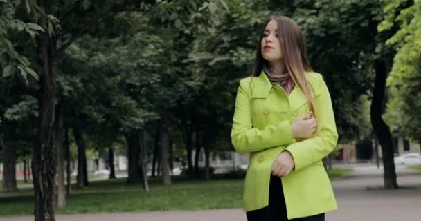 Femme en manteau jaune se promenant dans le parc de la ville à la fin de l'été ou à l'automne — Video