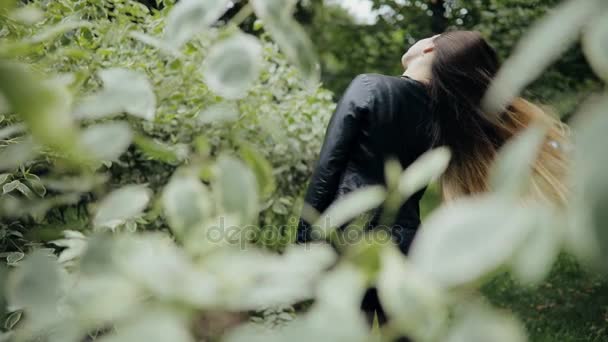 有魅力的女人，穿黑夹克扔在夏季公园，慢动作的头发 — 图库视频影像