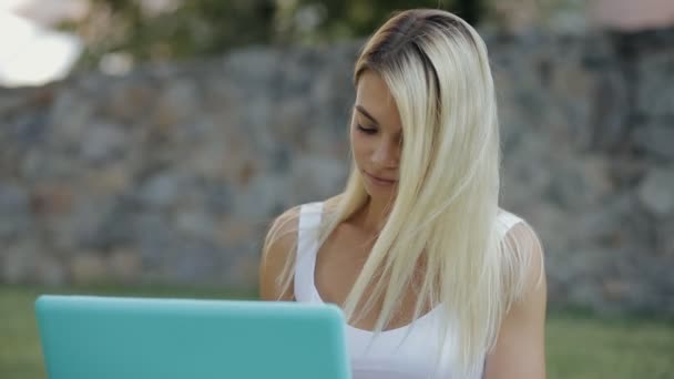그녀의 노트북 야외 공원에 잔디에 앉아 작업 하는 예쁜 여자 프리랜서 — 비디오
