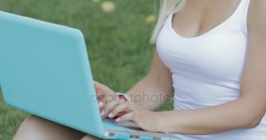 Güzel kadın, serbest meslek sahibi onun laptop açık park çimenlerin üzerinde oturan ile çalışma. Kamera ve gülümseme yüzünü ortaya.