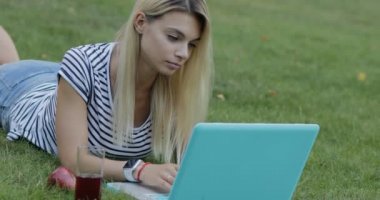 Güzel kadın blogger onu laptop açık park, o suyu içme çimenlerin üzerinde oturan ile çalışma