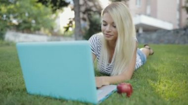 Güzel kadın blogger veya serbest meslek sahibi onu laptop parkta çim üzerinde yalan açık çalışma