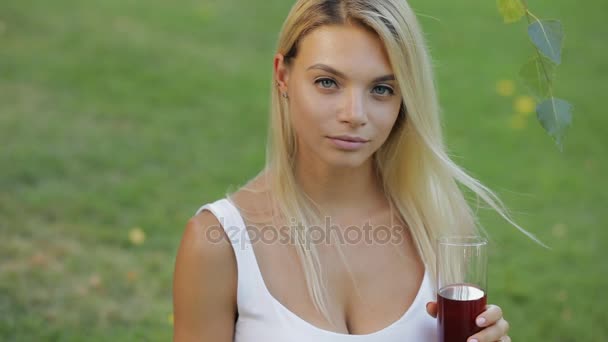 Napój zdrowy styl życia. Młoda kobieta daje granat sok siedzi na zewnątrz łąka w zwolnionym tempie — Wideo stockowe