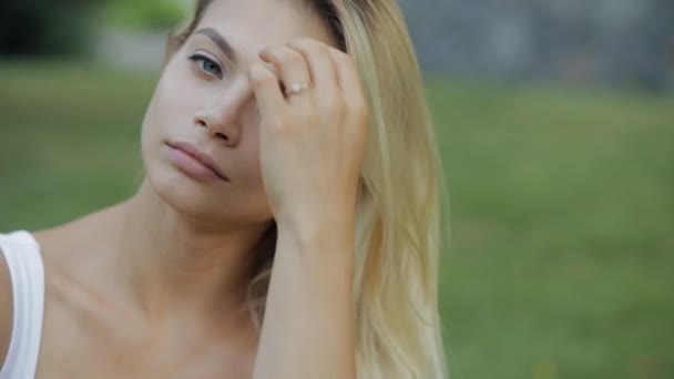 Hermoso retrato de mujer, cara de primer plano en cámara lenta, chica atractiva con hermoso cabello sentado en la hierba — Vídeo de stock