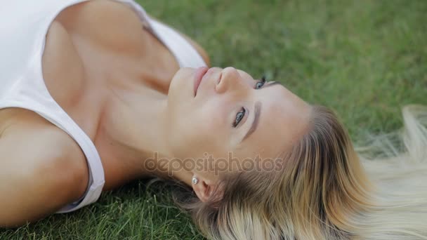 Belle femme relaxante allongée sur une herbe au ralenti, jolie fille avec de beaux cheveux profitant d'un repos — Video