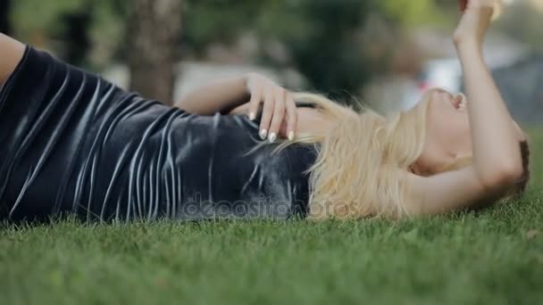 美丽的女人咯咯地笑着躺在慢动作的草地上 — 图库视频影像