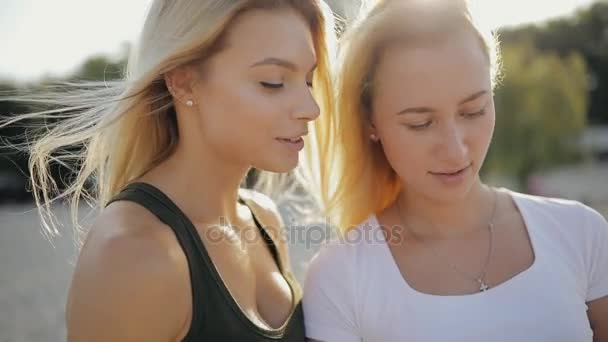 Meninas amigas olhando para smartphone em uma praia em férias de verão, câmera lenta — Vídeo de Stock