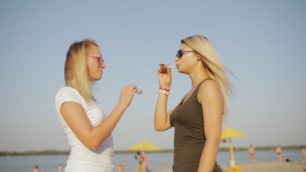 Chicas amigos sopla en un túbulo juguetes en una playa en las vacaciones de verano, cámara lenta — Vídeos de Stock