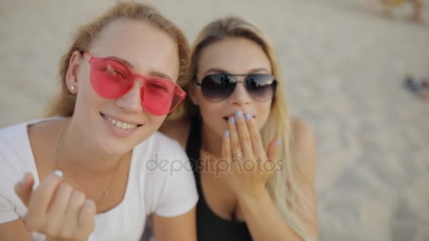 Flickor bästa vänner att göra flygande kyssar sitter på en strand som vilar tillsammans på sommarlovet i slow motion — Stockvideo