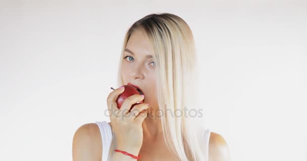 Mulher atraente na camisa comendo maçã vermelha isolada no fundo branco com som — Vídeo de Stock