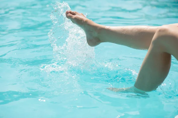 Coupé des jambes d'une femme dans l'eau de la piscine — Photo