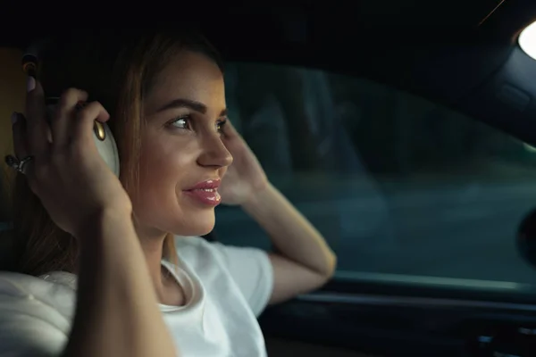 Mujer de lujo escuchar música con auriculares en su coche cómodo — Foto de Stock