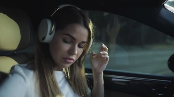 Πολυτελή γυναίκα να ακούσετε μουσική με τα ακουστικά στο αυτοκίνητό της άνετη, slowmotion — Αρχείο Βίντεο
