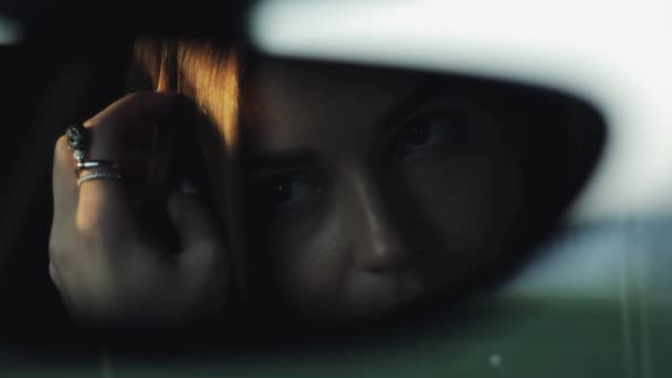 Luxe vrouw op zoek naar haar gezicht in de achteruitkijkspiegel van haar auto — Stockvideo