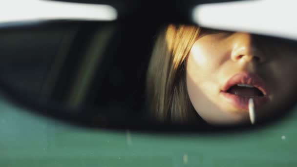Luxo mulher pinta seus lábios olhando para retrovisor espelho de um carro — Vídeo de Stock