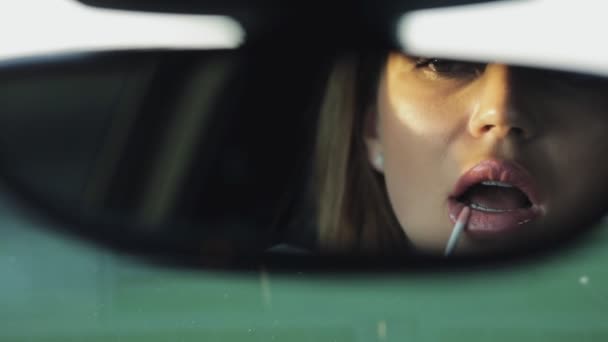 Mujer de lujo pinta sus labios mirando al espejo retrovisor de un coche — Vídeo de stock