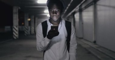 Gece Park smartphone yürüyüş kullanarak şapkalı Afrika adam