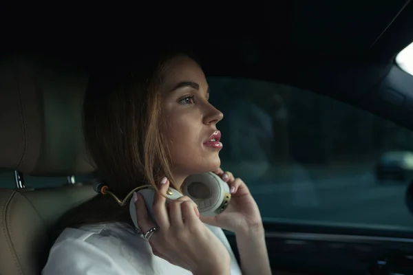 Luxury woman listen music with headphones in her comfortable car