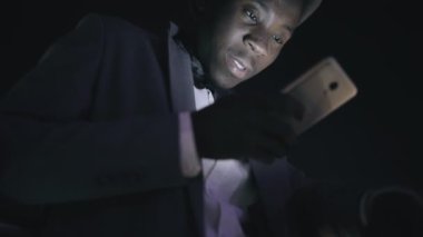 Gece şehir ayakta balkon akıllı telefon isteyen genç Afrika işadamı