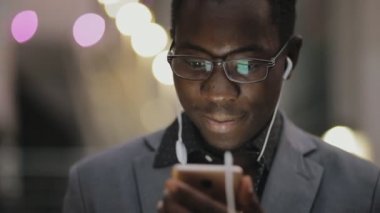 Kulaklıklar açık ile müzik dinlemek Klasik takım elbiseli genç Afrika öğrenci