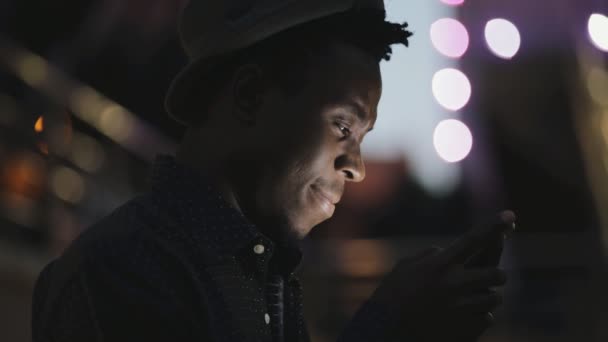 Afrika delikanlı Smartphone'a City gece aşağı bakıyor — Stok video