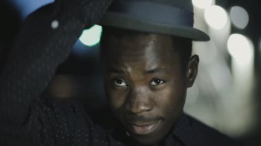 Genç Afrika adam portresi gece şehirde şapka giymek