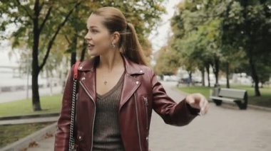 Sonbahar geliyor. Şarap rengi ceket kadında yürüyerek şehir sokak, slowmotion.