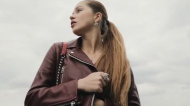 Bulutlu gökyüzü, slowmotion karşı bordo deri ceketli zarif kadın