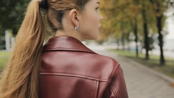 Llega el otoño. Mujer en chaqueta de color burdeos caminar en la calle de la ciudad, cámara lenta, vista trasera . — Vídeos de Stock