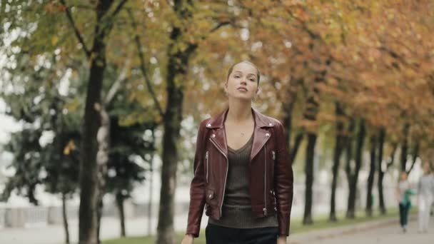 Llega el otoño. Mujer elegante en chaqueta de cuero color burdeos caminar en la calle de la ciudad, slow motion . — Vídeos de Stock