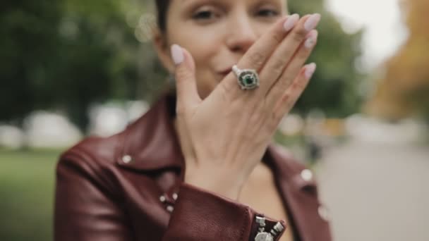 Mujer elegante en chaqueta de cuero de color burdeos hacen beso aéreo caminando en la calle de la ciudad, slow motion . — Vídeos de Stock