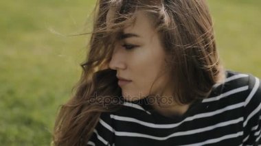 Mutlu kadınla çimenlerin üzerinde oturan yakın çekim portre sevimli yüzü slowmotion