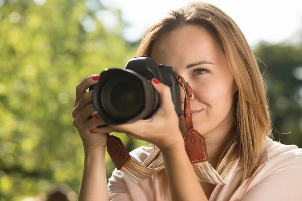 Mulher fotógrafo fazer atirar segurando câmera perto de seu rosto — Fotografia de Stock